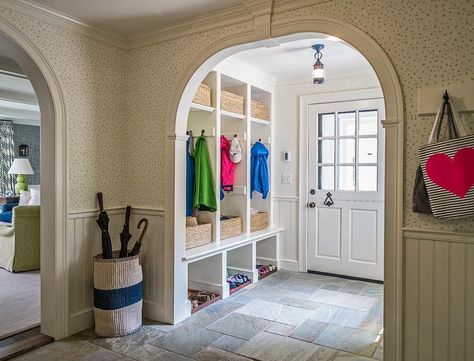 An arched doorway leads to a transitional mudroom filled with built-in open lockers lined with woven bins and coat hooks. Doorway Bench, Transitional Laundry Room, Small Mudroom Ideas, Basement Kitchenette, Arch Doorway, Mudroom Entryway, Modern Colonial, Mudroom Laundry Room, Basement Renovation