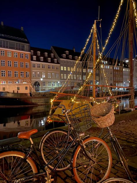 beautiful typical scenery of Copenhagen, pretty color houses in the side of a canal, surrounded by bikes and Christmas lights Copenhagen New Years Eve, Fall In Copenhagen, Living In Copenhagen, Copenhagen Fall Aesthetic, Autumn In Copenhagen, Copenhagen At Night, Copenhagen Winter Aesthetic, Copenhagen December, Christmas Copenhagen