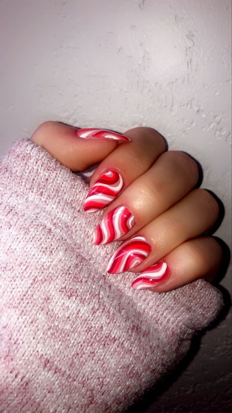 Hand posed with Red, Dark Red, and White Swirls painted on Almond-Shaped Nails Christmas Nails Swirls, Swirl Christmas Nails, Red And Green Swirl Nails, Christmas Swirl Nails, Red Glitter Swirl Nails, Red And White Swirl Nails, Peppermint Acrylic Nails, Red Swirl Nails, Nail Art Almond Shape