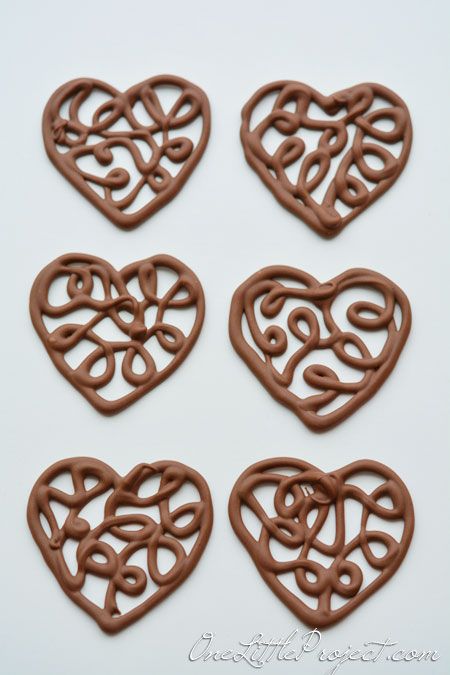 Here's an easy way to make chocolate filigree hearts. These would make the cutest cupcake toppers! Chocolate Hearts Decoration, Chocolate Cupcake Toppers Diy, Chocolate Swirls Decorations How To Make, Chocolate Cupcake Toppers, Heart Shape Chocolate, Chocolate Template, Heart Molds Silicone Ideas Chocolate, Chocolate Toppers, Chocolate Garnishes