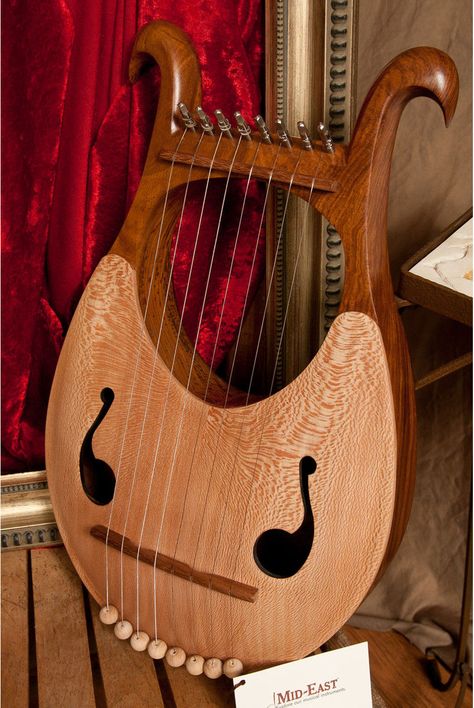 The solid sheesham body lends itself to the soft gentle curves of this eight string lyre. The eight metal strings provide a classical sound that is enhanced by the lacewood soundboard. When you are not playing, you can hang it up as a piece of art; it's that pretty. Tuning tool is included. Hold it upright on your lap or as you walk, and pluck both sides of the strings. Or lay it flat and pluck it. 10 inches wide by 17 inches long, 2.75 inches deep. There are a few suggestions for tuning.An auth Instrument Craft, Lyre Harp, Instrument Design, Celtic Harp, Early Middle Ages, Folk Instruments, Bagpipes, Musical Art, Worship Music