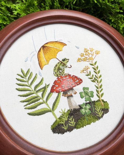 This cute embroidery pattern features a frog sitting on a mushroom holding an umbrella. He's trying to keep dry from the rain! This embroidery uses the technique of thread painting to create a whimsical 7 inch embroidery. Frog Embroidery Designs, Mushroom Embroidery Pattern, Embroidery Magic, Frog Embroidery, Frog And Mushroom, Mushroom Embroidery, Bee Embroidery, Thread Painting, Cute Embroidery