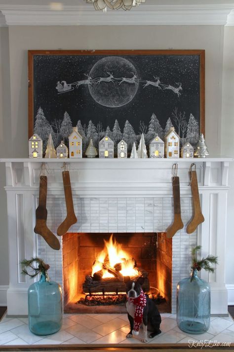 Love this chalkboard Christmas mantel with Santa in his sleigh, little white ceramic houses and antique stocking stretchers kellyelko.com #christmas #christmasmantel #farmhousechristmas #christmaschalkboard #chalkboardart #christmasdecorating #christmashometour #vintagechristmas Apartment Christmas, Christmas Chalkboard, Christmas Mantel Decorations, Christmas Mantle, 2023 Trends, No Place Like Home, Home Christmas, Christmas Mantels, The Fireplace