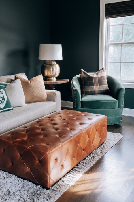 This prior underused office was turned into a loungy tv den. We added hardwood to some areas that previously had a few built-ins. Deneen suggested a dark green to create a moody atmosphere and match the vibe the client wanted. She added velvet green swivels, a sofa that pulls out into a large chaise and a gorgeous leather ottoman. Gold lamps and décor complete this room, making it feel cozy. Moody Den, Green Sofa Decor, Tv Den, Ottoman Gold, Gold Lamps, Bonus Room Design, Large Chaise, Moody Atmosphere, Brown Leather Ottoman