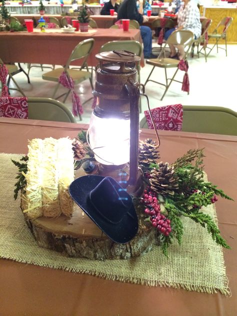 centerpieces were log rounds set atop burlap runners. battery powered LED lanterns with country greenery, mini hay bales, mini cowboy hats ,etc. Simple Cowboy Centerpieces, Quebradita Party, Western Arrangements, Cowboy Party Centerpiece, Mini Cowboy Hats, Western Christmas Party, Cowboy Centerpieces, Western Centerpieces, Family Reunion Decorations