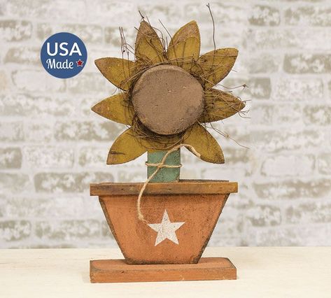 The Potted Sunflower is a decorative sunflower and pot figurine made of raw distressed wood with a painted finish. The piece includes twig detailing, a jute tie, and a rectangular wooden base for a freestanding display. This sunflower makes a rustic and charming addition to a porch, shelf, or table during the spring and summer season. Measures 16.5” high by 9.5” wide by 3.5” deep. Made in the USA! Wood Sunflower, Fall Party Decorations, Primitive Lighting, Craft Booth Displays, Holiday Decorating Ideas, Booth Displays, Battery Operated Candles, Craft Booth, Wooden Flowers