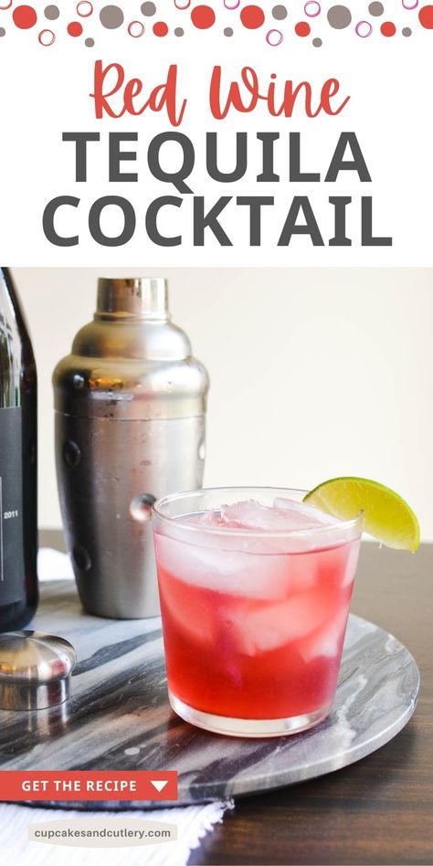 A red cocktail in a glass on a tray next to a cocktail shaker.