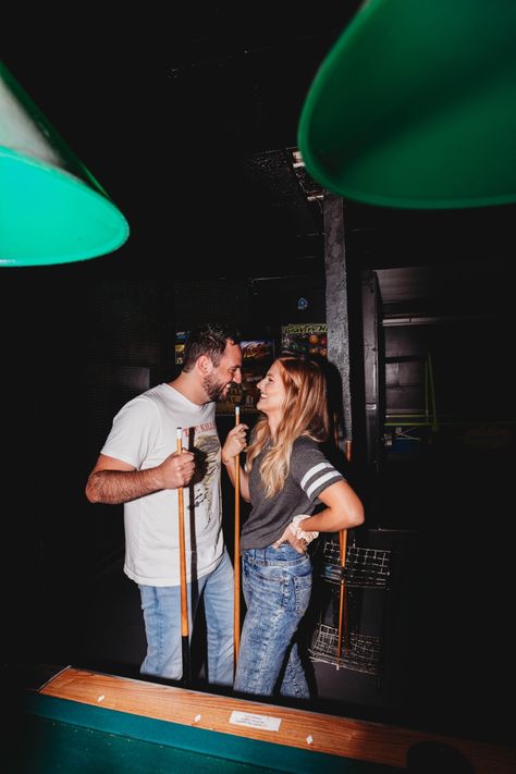 Cute couple in jeans + tshirts playing pool and laughing. In a vintage arcade Pool Hall Engagement Photos, Engagement Photos Playing Pool, Billiards Engagement Photos, Pool Table Engagement Photos, Billiard Couple, Arcade Couple Pictures, Arcade Engagement Photos, Dive Bar Engagement Photos, Couple Playing Pool