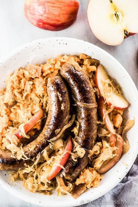 Looking down on a plate of bratwurst and sauerkraut on potatoes with some apple slices beside the plate. Brats With Sauerkraut, Sauerkraut With Apples, Sauerkraut And Apples, Bratwurst And Sauerkraut, Brats And Sauerkraut, Aip Dinners, Savory Apple Recipes, Grilled Brats, Bratwurst Recipes