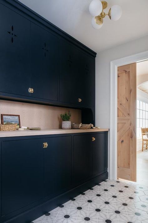 Kitchen features black flat front butlers pantry cabinets with vintage brass latch hardware, gray wash wooden countertops, black and white geometric floor tiles and a reclaimed wood pocket door. Pantry Pocket Door, Dark Blue Cabinets, Floor To Ceiling Storage, Blue Entryway, Transitional Laundry Room, Wooden Desk Chairs, White Pantry, Latches Hardware, Kate Marker Interiors