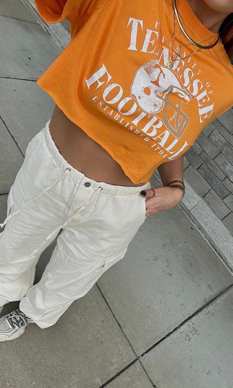 It's football season in KNOXVILLE! This tee is UT orange with a vintage inspired football graphic - grab it for the upcoming game! University of Tennessee licensed. Comes cropped or uncropped. Model is 5'6" with a 32DD bust, 27" waist, 36" hips, and wearing a medium. Model usually wears size 2/4. This item runs true to size! Vols Football Game Outfit, Tennessee Orange Outfit, Tennessee Volunteers Gameday Outfits, Ut Gameday Outfit Tennessee, University Of Tennessee Outfits, Tennessee Vols Outfit, Utk Gameday Outfit, Tennessee Football Outfits, University Of Tennessee Gameday Outfit