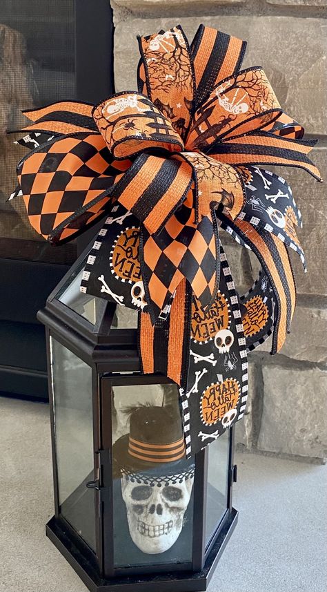 Add this Halloween bow to your favorite wreath, lantern or home decor. Black, orange white. Happy Halloween print, stripes, skeletons, Harlequin patterns of ribbons. The edges are wired for easy fluffing when removed from the box. Made with two 7" stems of floral wire on back to attach to almost anything. Measures 10" x 10 with tail/streamers that vary in length to 8". Halloween Ribbon Crafts, Lantern Toppers, Halloween Floral Arrangements, Door Hanger Bow, Bow Door, Halloween Gift Baskets, Wreath Inspiration, Homemade Halloween Decorations, Lantern Ideas