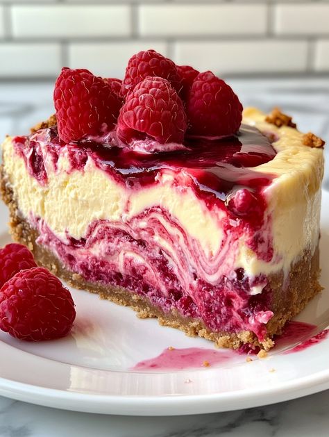 Lemon Raspberry Swirl Cheesecake with a Surprise Center 🍋   𝗜𝗻𝗴𝗿𝗲𝗱𝗶𝗲𝗻𝘁𝘀 👍  - 2 cups graham cracker crumbs - 1/2 cup unsalted butter, melted - 4 (8 oz) packages cream cheese, softened - 1 1/4 cups granulated sugar - 1 teaspoon vanilla extract - 4 large eggs - 1/2 cup sour cream - 1/4 cup heavy cream - Zest of 2 lemons - 1/4 cup fresh lemon juice - 1/2 cup raspberry jam, warmed - 1 cup fresh raspberries - 1 cup white chocolate chips Fresh Raspberry Desserts, Raspberry Swirl Cheesecake, Swirl Cheesecake, Raspberry Desserts, Fresh Raspberries, Raspberry Cheesecake, Lemon Raspberry, Sweet Snacks Recipes, Raspberry Jam