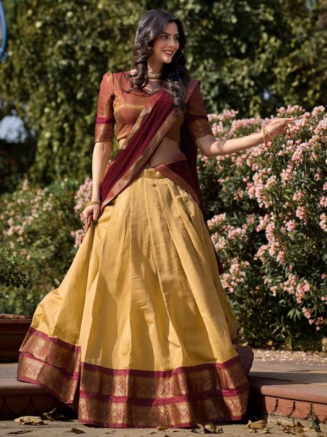 Introducing an exquisite ensemble that embodies the rich heritage of Kanchipuram silk – a cream color Kanchipuram silk lehenga paired with a maroon choli and a matching maroon georgette dupatta. This stunning attire is meticulously crafted to bring out the elegance and sophistication of traditional Indian craftsmanship. The cream lehenga is adorned with intricate zari weaving work, offering a luxurious and opulent appearance that is perfect for grand occasions. The lehenga, tailored to perfectio Kerala Traditional Dhavani Set, Cream Kanchipuram Silk Saree, Kerala Saree Blouse Designs Traditional, Trendy Half Saree Designs, Kerala Half Saree Designs, Half Saree Blouse Designs, South Indian Lehenga, Cream Lehenga, Silk Half Saree