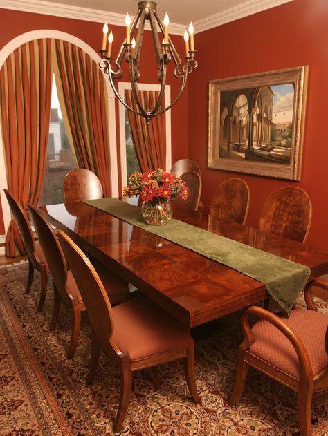 This bold dining room features rust-colored walls and rust, olive and gold draperies that emphasize the shapes of the windows. Formal Dining Room Ideas Traditional, Red Dining Room Ideas, Red Dining Room, Eclectic Dining Room, Boho Dining Room, Colorful Kitchen Decor, Eclectic Dining, Vibrant Living Room, Transitional Dining Room