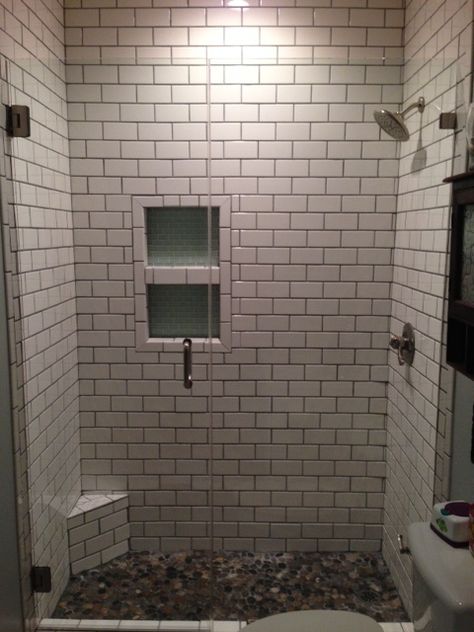 Our customer in Charleston, SC has a small condo. They wanted to remove their iron 60" tub/shower and replace it with a tile shower. The transformation was dramatic. We used a TileRedi pan, white subway tile with gray grout and a river rock floor and a frameless shower door. The insert is glass tile with white grout. Pebble Shower Floor Dark Grout, White River Rock Shower Floor, White Subway Tile Shower With River Rock Floor, Black And Gray Pebble Shower Floor, Pebble Stone Shower Floor Subway Tile, River Rock Floor, Rock Floor, Gray Grout, Norfolk House