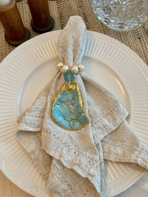 Add coastal elegance to your table with these handmade Serena and Lilly-inspired turquoise oyster shell napkin rings! Decoupage on the inside, gold-brushed wood beads, hand-painted gilded gold on the trim and outside of shell. Each shell is finished with a layer of sealer for protection and durability. Grand Millennial Coastal, Oyster Shell Napkin Rings, Oyster Shells Diy, Shell Napkin Rings, Oyster Shells Decor, Shell Diy, Rings Turquoise, Shells Diy, Grand Millennial