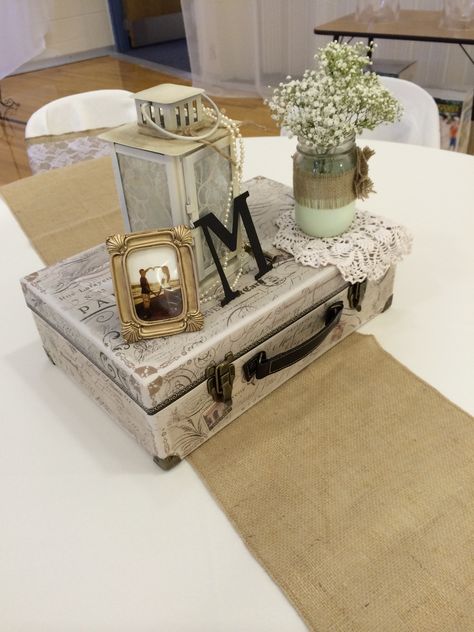 Vintage centerpiece using a suitcase, lantern with pearls, jars dipped in paint with baby's breath, and a picture of the couple. Suitcase Centerpiece Ideas, Suitcase Centerpiece, Vintage Suitcase Centerpiece, Suitcase Centerpieces Travel Themes, Vintage Wedding Centerpieces Pearls, Old Suitcase Wedding Decor, Suitcase Wedding Card Holder, Travel Centerpieces, Vintage Suitcase Wedding Cards