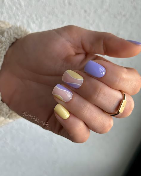 Close-up of a hand with short nails painted in pastel lavender and yellow hues, featuring subtle white swirl accents for a clean and sophisticated manicure, ideal for spring. Yellow And Purple Nails Ideas, Pastel Yellow And Purple Nails, Lavender And Yellow Nails, Short Swirl Nails, Lavender Nails Short, Purple Yellow Nails, Purple And Yellow Nails, Swirl Nail Art, Swirl Nails