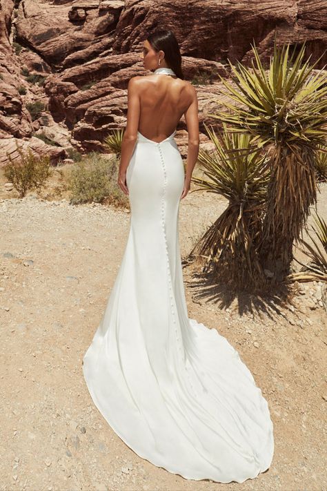 Let your inner siren of the sea emerge in our captivating Lucia gown! Her sexy sheath silhouette hugs every curve much like the gentle embrace of ocean waves. Her daring backless design is paired with a modest high neckline and romantic button details on the train to create the ultimate traditional wedding dress design. Speaking of her backless design, it can be adjusted with a removable back cowl, offering brides a small change between ceremony and reception. Halter Backless Wedding Dress, High Neck Halter Wedding Dress, Sima Couture, Wedding Gown Halter, Halter Wedding, Spaghetti Strap Wedding Dress, Fairy Wedding Dress, Halter Wedding Dress, Anne Barge