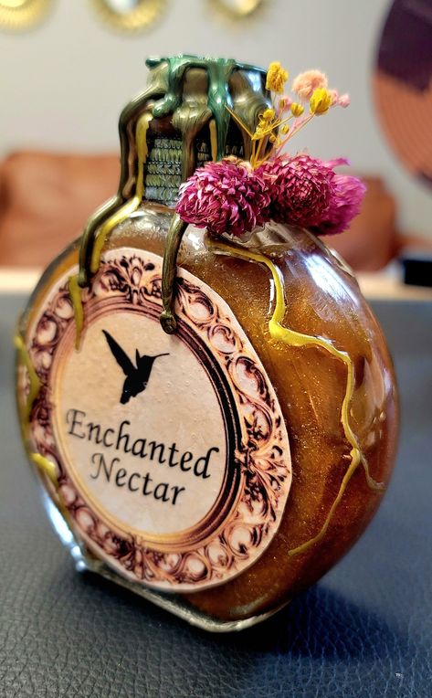 Step into the mystical realm with our Enchanted Nectar Potion Bottle - a glass-crafted masterpiece that transcends the ordinary. Meticulously handcrafted with an unwavering attention to detail, this bottle is not just an accessory; it's a bewitching fusion of witchy charm, boho elegance, and earthy allure designed to elevate your home decor. The Enchanted Nectar Potion Bottle beckons with its entrancing design, featuring an exquisite blend of botanical and floral elements. Crafted with a touch of magic, this bottle captures the essence of an otherworldly elixir, bringing a sense of enchantment to any space. Designed for those who embrace the unconventional and appreciate the ethereal, this potion bottle is a unique statement piece. With crystals carefully embedded within, it creates a mesm Potion Maker Character Design, Witch Potions Aesthetic, Weird Bottles, Witchy Potion Bottles, Truth Potion, Witch Potions, Vintage Glass Bottles, Bristol Tn, Witchy Boho