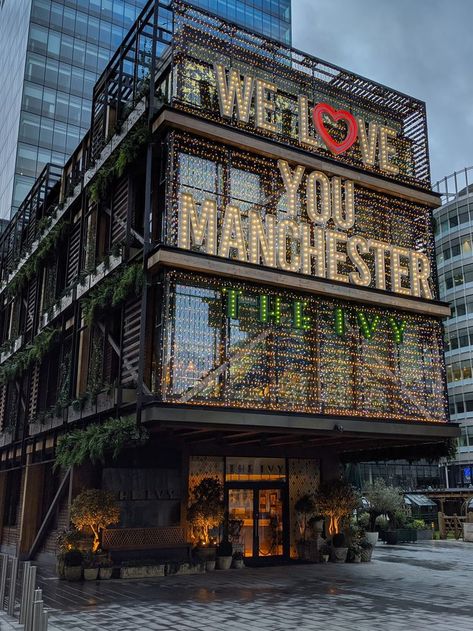 Modern building at twilight with illuminated text We Love You Manchester and The Ivy Manchester City Centre Aesthetic, Manchester Instagram Story, Manchester In Winter, Living In Manchester, Manchester England Aesthetic, Manchester Apartment Aesthetic, Manchester Uk Aesthetic, University Of Manchester Aesthetic, Uni Of Manchester