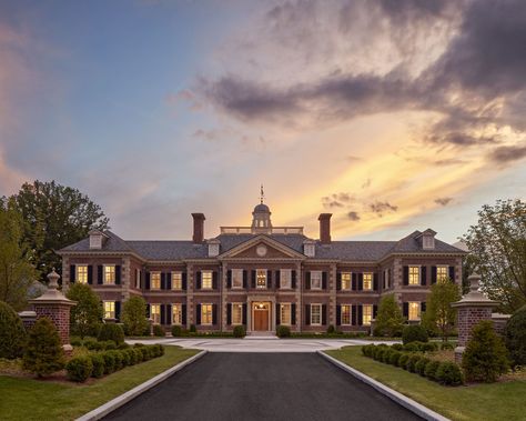 Thoughtful consideration was taken in the selection of the brick’s blend of red tones, which are complemented by the soft warm hues of the sandstone accents on this new Georgian style estate. #brickpiers #slateroof #limestonequoins #redbrickhouse #cupola #pedimentedentry #drivecourt #symmetricalarchitecture #georgianarchitecture #traditionaldesign #classicalarchitecture #sunset #newenglandestate Red Brick Mansion Exterior, Brick House Mansion, Georgian Style Architecture, Red Brick Mansion, Bloxburg Colonial Mansion, Brick Mansion Exterior, Colonial Mansion Exterior, Georgian Style Homes Exterior, Brick Georgian House