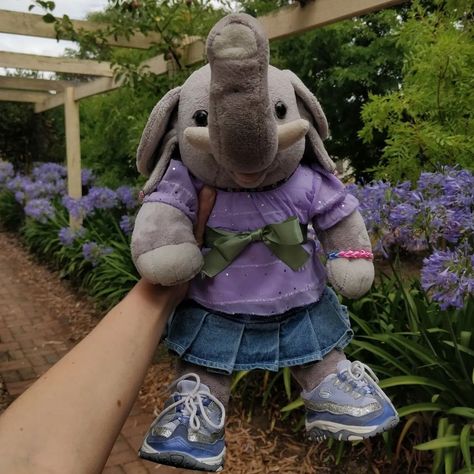 Build-a-bear elephant wearing a purple outfit and purple flowers in the background Build A Bear Outfits Y2k, Build A Bear Workshop Aesthetic, Build A Bear Aesthetic, Lola Aesthetic, Build A Bear Accessories, Elephant Fashion, Totes Ideas, Build A Bear Outfits, Bear Images