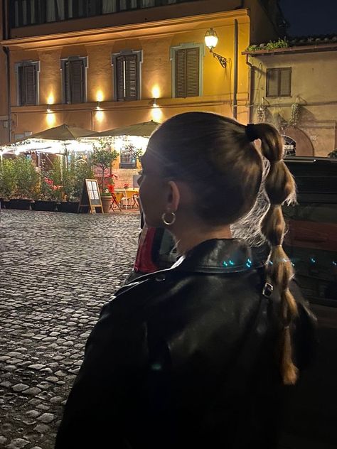 Girl turned around facing a restaurant in Rome, Italy. She is wearing a black leather jacket with her hair in a high ponytail with bubble braids. Fashion Outfits Leather Jacket, Italy Night Aesthetic, Hair Dark Aesthetic, Night Out Looks Winter, Going Out Outfits Cold, Hair Styles Winter, Dark Aesthetic Pictures, Bubble Braid Ponytail, Braid Aesthetic