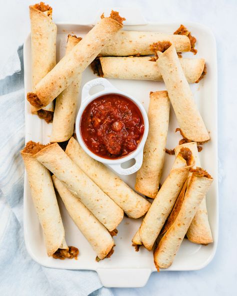 These oven baked flautas are filled with a zesty refried bean and cheese filling! Similar to taquitos, they can be made with either flour or corn tortillas. #flautas #taquitos #mealprep #mexican #snack Baked Flautas Recipe, Baked Flautas, Baked Taquitos, Refried Bean, Canning Refried Beans, Homemade Refried Beans, Roasted Tomato Salsa, Salsa Guacamole, Easy Guacamole