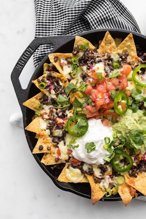 Close up of the finished loaded nachos just after baking topped with salsa, sour cream, and guacamole Lentil Nachos, Nachos Vegetarian, Nachos Recept, Spicy Guacamole, Eating Tacos, Loaded Nachos, Melty Cheese, Nachos Recipe, Corn Chips