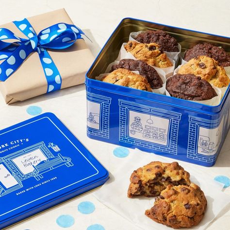 Elevate the joy of Levain cookies with our signature tin — a delightful gift that combines 8 iconic cookies and a lasting memento in our classic blue hue. An homage to our roots, the signature tin features our West 74th Street bakery, where our founders Connie & Pam first made our iconic cookie back in 1995. The charming blue tin holds 8 cookies packed in beautiful cellophane bags with hand-tied blue ribbons. The tin helps to keep cookies fresh on the counter and serves as a sweet memento long a Cookie Tin Packaging, Cookies Box Design, Luxury Food Packaging, Cookie Branding, Cookie Gift Packaging, Cookie Package, Levain Cookies, Insomnia Cookies, Tin Packaging