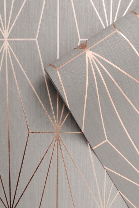 This stylish Kayla Geometric Wallpaper would make a great statement in most rooms of your home. The design features a geometric pattern of elongated triangles with a contemporary metallic rose gold finish that catches and reflects the light. This is set on a soft grey matte background with a subtle lined texture. Easy to apply, this high quality wallpaper would look great when used to create a feature wall or to decorate an entire room. Wallpaper Bedroom Feature Wall, Geo Wallpaper, Feature Wall Bedroom, Wallpaper Inspiration, Building Remodeling, Metallic Wallpaper, Grey Roses, Drinks Cabinet, Gold Wallpaper