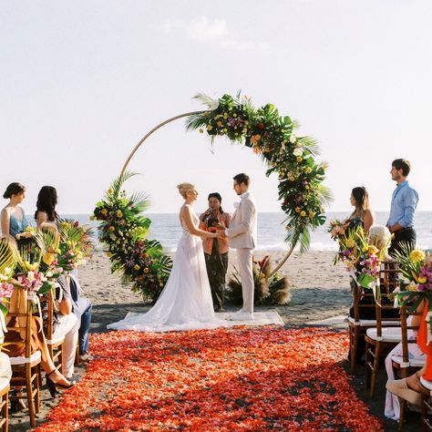 The brief was a tropical-boho blend, and it couldn’t have turned out more beautiful. A gold circle arch decked out with local blooms like orchids, frangipani, and anthuriums in soft whites, blush, coral, and flamingo tones. A beachside setup with a cozy rug, rose petals lining the aisle, and the ocean as the backdrop. We loved every moment of bringing Jasmin and Marcel’s vision to life. Planner: @bali.loveweddings Venue: @villavedasbali Florist: @natafloristbali Furniture & Decor: @balisew... Beachfront Wedding, Tropical Weddings, Circle Arch, Wedding Setup, All Inclusive Wedding Packages, Wedding Beach Ceremony, Wedding Set Up, Bali Wedding, Breathtaking Wedding