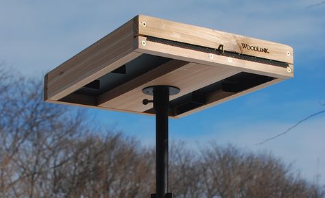 A wooden tray bird feeder is installed on the top of a pipe bird feeder stand. Tray Bird Feeder Diy, Large Bird Feeders To Build, Diy Bird Feeder Easy Wood, Bird Platform Feeder Diy, Bird Feeder Platform, Bird Feeder Tray Platform Diy, Platform Bird Feeder Diy, Diy Bird Feeding Station, Diy Bird Feeder Wooden