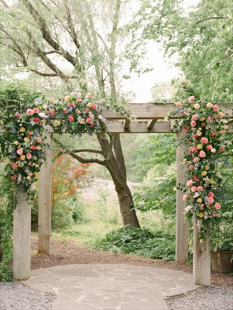 Two "swags" of dusty blues, lavendars, peach, pinks, ivory, creams, and soft yellows are designed on this hand made pergola with growing, wild, wisteria! Pergola For Wedding Ceremony, Pergola Floral Decor, Flowers On Pergola Wedding, Wedding Pergola Flowers, Floral Pergola, Pergola Wedding Decorations, Pergola Flowers, Arbour Wedding, Pergola Wedding