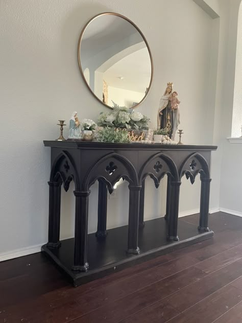 I found the buffet table at a garage sale, but it can be purchased here: https://luxeleatherfurniture.com/shop/living-room/accent-tables/gothic-sofa-table/ The round mirror and all table decor except the statues and rosarg are from At Home. The Mary statues were purchased at a local Catholic store. Rosary can be purchased on Etsy through smallthingsgr8love. Gothic Console Table, Gothic Decor Aesthetic, Gothic Entryway Decor, Gothic Table Decor, Goth Catholic Aesthetic, Goth Entryway, Catholic Gothic Aesthetic, Goth Farmhouse Decor, Gothic Minimalist Decor