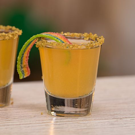 St. Patrick's Day cocktails don't get any crazier looking than these Pot O' Gold Shots. These little St. Patrick's Day Shooters mix up orange vodka and pineapple juice, and are garnished with gold luster dusty, gold sprinkles, and rainbow candy strips. We promise there are no better St. Paddy's Day shooters than these little bad boys! Candy Garnish Cocktails, Orange Shots Alcohol, Pot Of Gold Cocktail, Gold Shots, Orange Shots, Bar Management, Holiday Bars, Orange Crush Cocktail, Ginger Beer Drinks