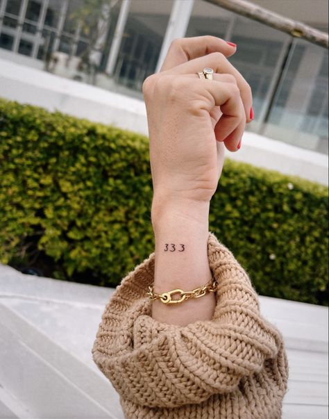 A woman’s for showing an angel number tattoo on the outside of her wrist, it says 333. 333 Minimalist Tattoo, Fine Line 333 Tattoo, 333 Wrist Tattoo, Vertical Number Tattoo, Fine Line Angel Number Tattoo, Angel Number 333 Tattoo, 333 Angel Number Tattoo Ideas, 4 Life Tattoo, 333 Angel Number Tattoo