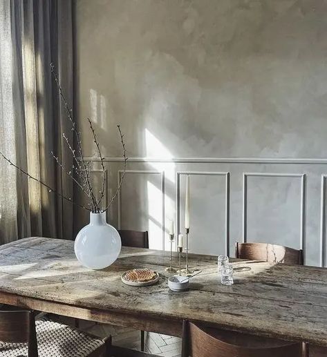 a refined dining room with grey limewashed walls, a rough wooden table, stylish chairs and grey curtains plus a white vase for decor Green Limewash Wall, Green Limewash, Limewashed Walls, Green Upholstered Bed, Limewash Wall, Lime Wash Walls, Limewash Walls, Vintage Inspired Bedroom, Lime Wash