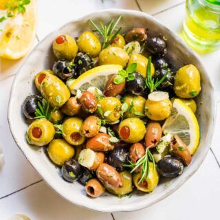 Marinated Olives olives in bowl with fresh herb and lemon garnishes Olive Marinade, Marinated Olives Recipe, Easy Party Foods, Appetizer Recipes Easy, Olive Oil Marinade, Dinner Then Dessert, Fancy Appetizers, Holiday Appetizers Recipes, Marinated Olives