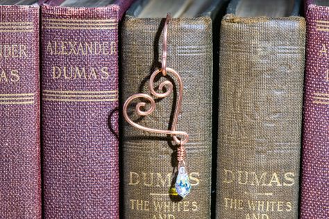 This hammered copper bookmark featuring a hand-bent wire heart makes a great gift! For yourself, for a teacher, for a wife or girlfriend, or anyone in your life who enjoys good books. The open spiral heart design features a super-sparkly swarovski crystal teardrop dangle, with an AB (aurora borealis) coating on the back side to really amp up the sparkle and reflections. The copper shepherd's crook bookmark features a tight spiral at the bottom, and has been hammered to flatten it and add interes Copper Bookmark, Purse Charms Diy, Wire Bookmarks, Copper Wire Crafts, Crafting Wire, Heart Bookmark, Wire Craft, Bookmark Ideas, Wire Heart