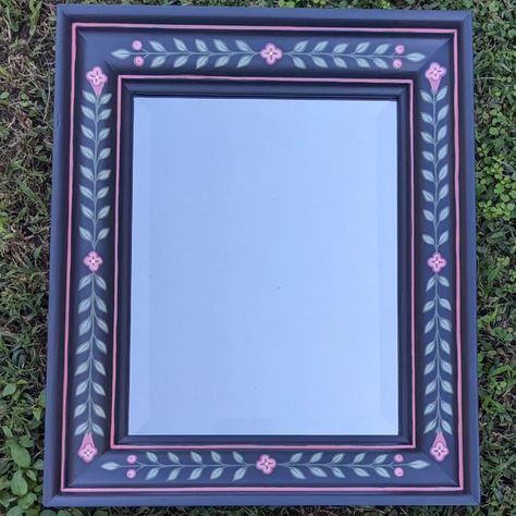 Still working my way through these mirrors 😁 Rectangle beveled mirror hand painted with bright pink flowers on a blue toned charcoal background with lots of leaves #handpaintedpictureframe #paintedframe #handpainted #handpaintedfurniture #colorfulhome #colorfulinterior #interiordesign #folkart #boho #bohostyle #bohodecor #botanicalart #botanical #uniqueinteriors #fusionmineralpaint #handpainteddecor #smithfieldva #virginiaartist #upcyclefurniture #upcycle Painting Wooden Mirror Frame, Painted Wooden Mirror Frame, Funky Painted Mirror Frames, Painted Mirror Frame, Floral Border Mirror, Handpainted Wood Mirror, Painting Mirror Frames, Hand Painted Mirrors, Floral Mirror