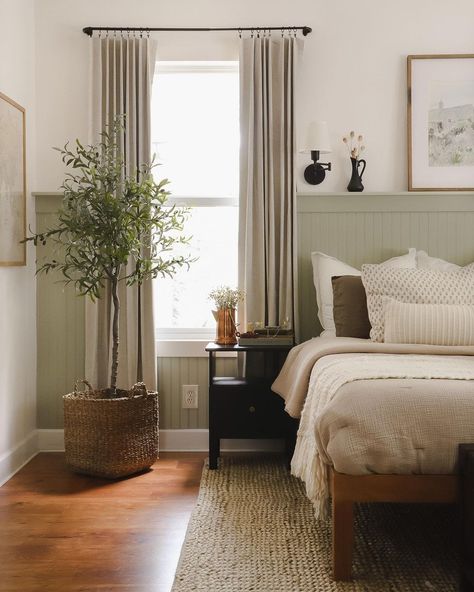 I wish this were my dreamy cottage bedroom. The color palatte is so beautiful, and all the natural materials in the room make it feel so grounded. The most impactful part of this room is the accent wall with the pale sage green wainscoting. This adds some color and life to the room and acts as a headboard substitute for the bed and a hidden shelf for extra dÃ©cor items. Light Sage And Cream Bedroom, Sage Green Wainscoting Bedroom, Cottage Bedroom Wainscoting, Light Sage Accent Wall, Gray Green Wainscotting, Cream Sage Bedroom, Pale Green Furniture, Bedroom Light Green Accent Wall, Sage Green Natural Bedroom