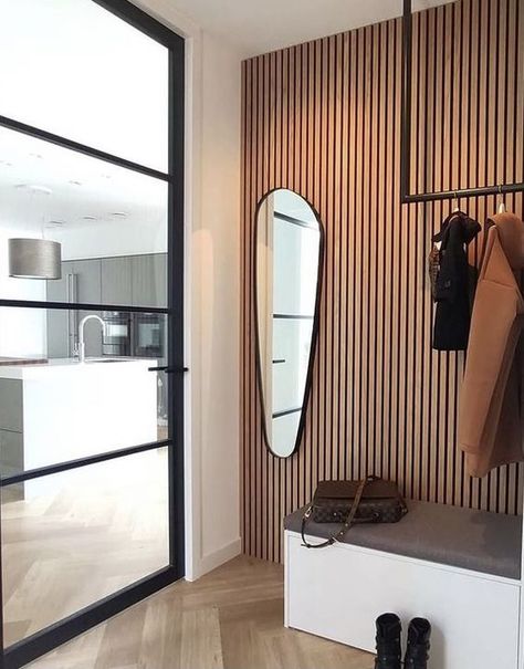 a chic entryway with a wood slat accent wall, a storage bench, a rack and an asymmetrically shaped mirror plus a glass door Slat Wall Ideas, Wood Slat Accent Wall, Slat Accent Wall, Light Stained Wood, Chic Entryway, Monochromatic Living Room, Wall Bench, Neutral Curtains, Contemporary Seating