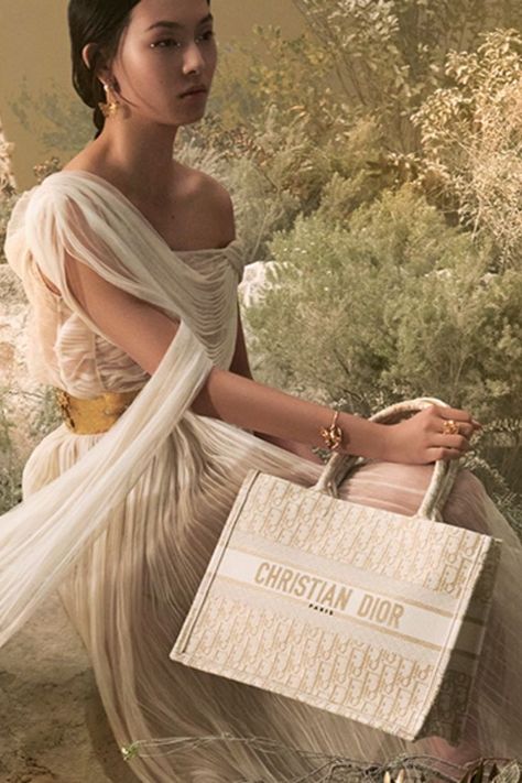 In this wintry fairy-tale forest setting inspired by the eternal beauty of Greece and the Dior Cruise 2022 collection by Maria Grazia Chiuri, discover a magical version of the emblematic ‘Dior Book Tote’, an essential emblem of the Dior aesthetic, revisited in a fully embroidered cream and gold version of the House’s ‘Dior Oblique’ motif. © Elina Kechicheva Dior Book Tote Outfit, Dior Aesthetic Outfit, Greek Goddess Photoshoot, Elina Kechicheva, Dior Photoshoot, Greek Style Dress, Sand Aesthetic, Ancient Greece Aesthetic, Perfume Adverts