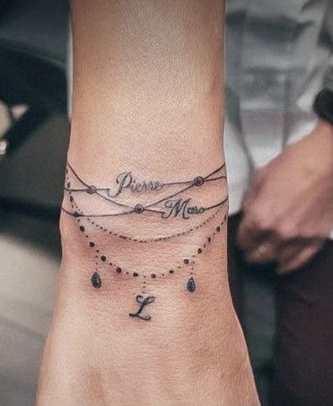 Ankle Bracelets Tattoos For Women, Simple Wrist Tattoo, Braclet Tattoo, Wrist Hand Tattoo, Symmetrical Tattoos, Charm Bracelet Tattoo, Wrap Around Wrist Tattoos, Family Tattoo Ideas, Word Tattoo Ideas