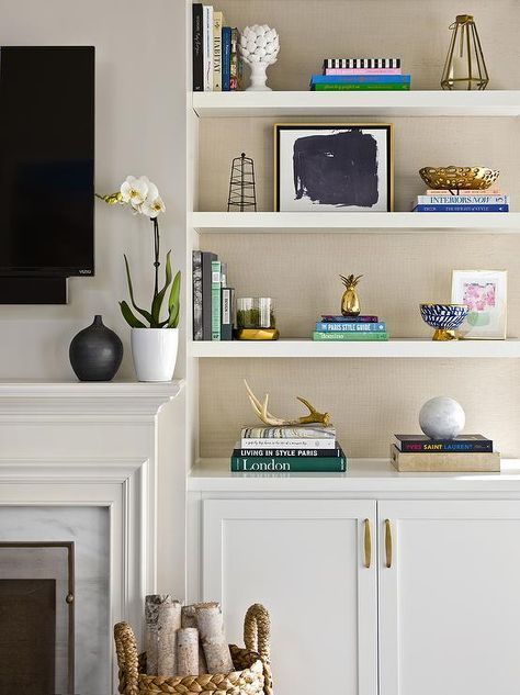 Feb 17, 2020 - Beautifully decorated transitional living room is equipped built-in styled white shelves accented with tan wallpapered backs and positioned above white cabinets adorning brass pulls. Wall Shelf Decorating Ideas, Shelf Decorating Ideas, Backing Ideas, Shelves Living Room, Shelf Decorating, Wall Shelves Living Room, Living Room Wallpaper, Floating Shelves Living Room, Built In Shelves Living Room