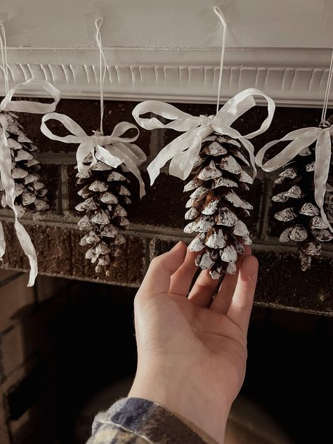 These delicately adorned pine cones add the perfect element of nature's beauty to your winter home. Each cone was carefully selected from the forest floor on a blustery autumn day, painted with festive/seasonal colors, and tied with a bow to complete their look of elegance. Whether they are hanging from the edge of your mantel, strung across window panes, or dangling from the boughs of your Christmas tree, these pinecones are a delightful addition to your Holiday season decor! Xmas Pine Cone Decorations, Pinecone Trees Diy, Decoration Noel Nature, After Christmas Winter Decor, Eco Friendly Christmas Decorations, Pine Cone Ornaments, Pinecone Art, Snowy Pinecone, Pine Cone Christmas Decorations