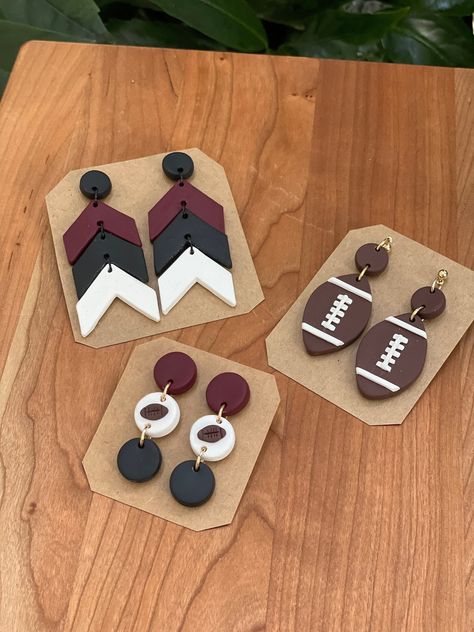 Garnet, black & white dangles. Football dangles Football Jewelry Diy, Football Craft Ideas, Clay Football Earrings, Football Polymer Clay Earrings, Polymer Clay Football Earrings, Football Clay Earrings, Sports Earrings, Football Jewelry, 2024 Jewelry